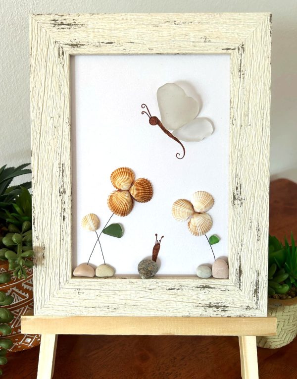 A lovely scene with a butterfly, snail, and flowers, made with seaglass and seashells, perfect as a unique gift!